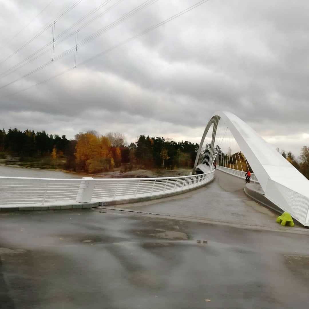 Vit modern gångbro som leder till Blåbärslandet, i bakgrunden.